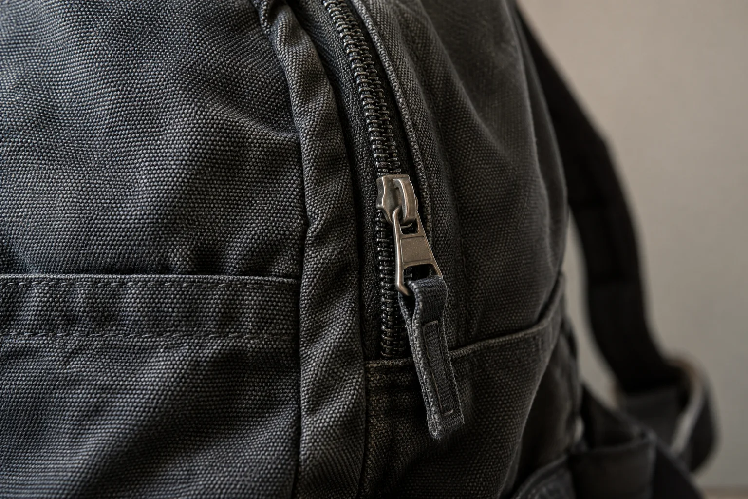 Detail švu, zipu a materiálu látkového batohu.